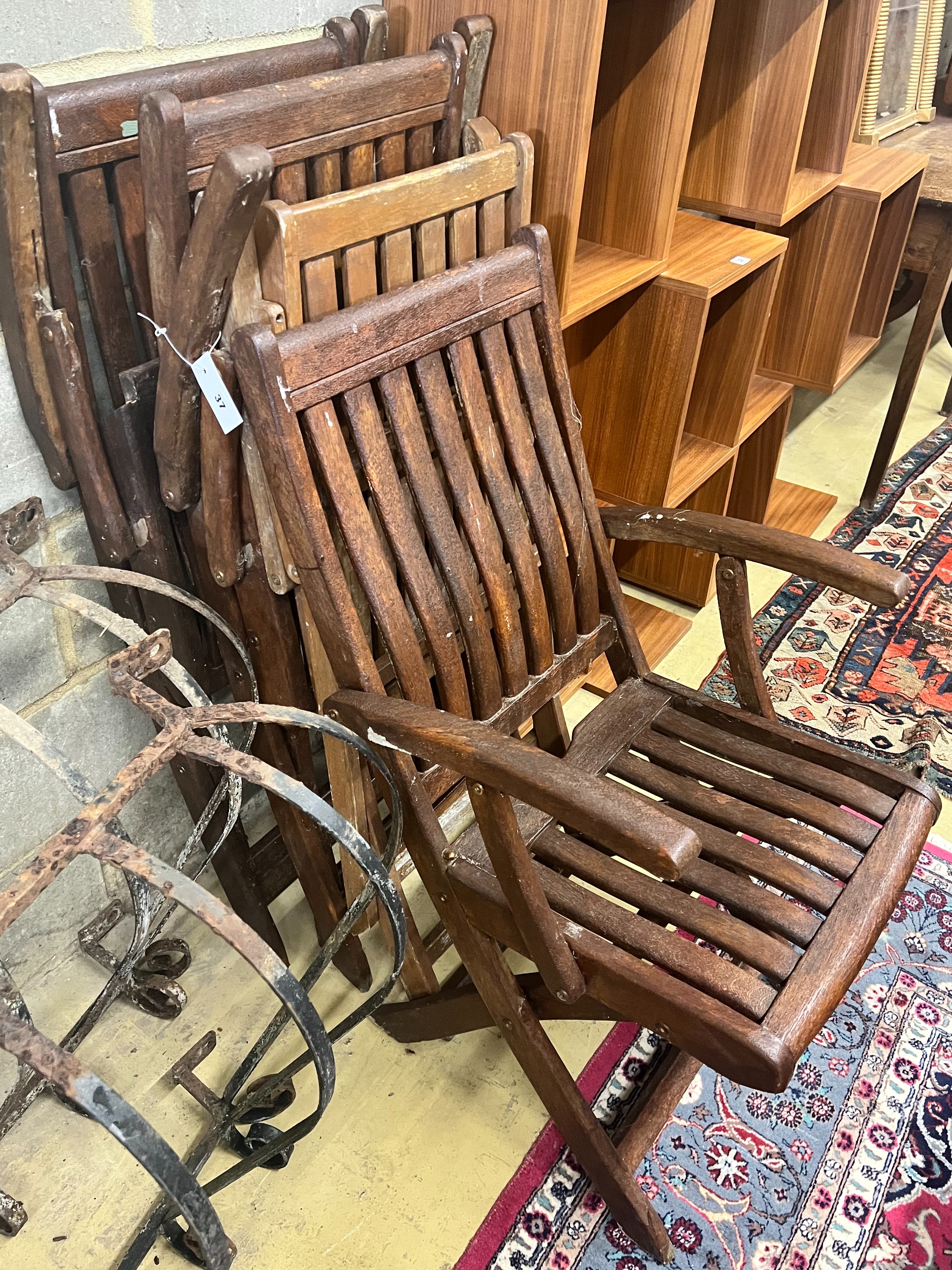 A set of four stained teak folding garden elbow chairs
